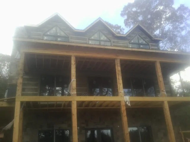 Dormers and porch framing on a large log home under construction — Roof Coating work by our crew in Dunbarton