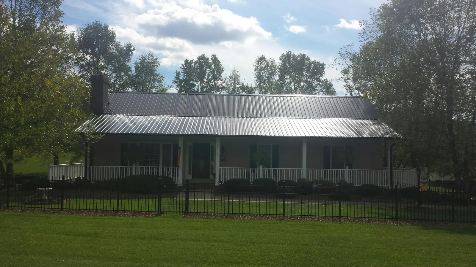 Gray metal roof on a brick ranch with a full width front porch — Gutter Guard Installation work by our crew in Dunbarton